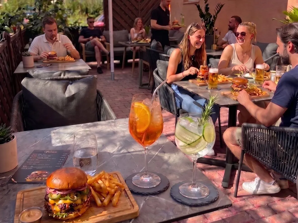 Terrasse im Innenhof von Onkel Emma: Gäste mit Burgern, Bier und Cocktails